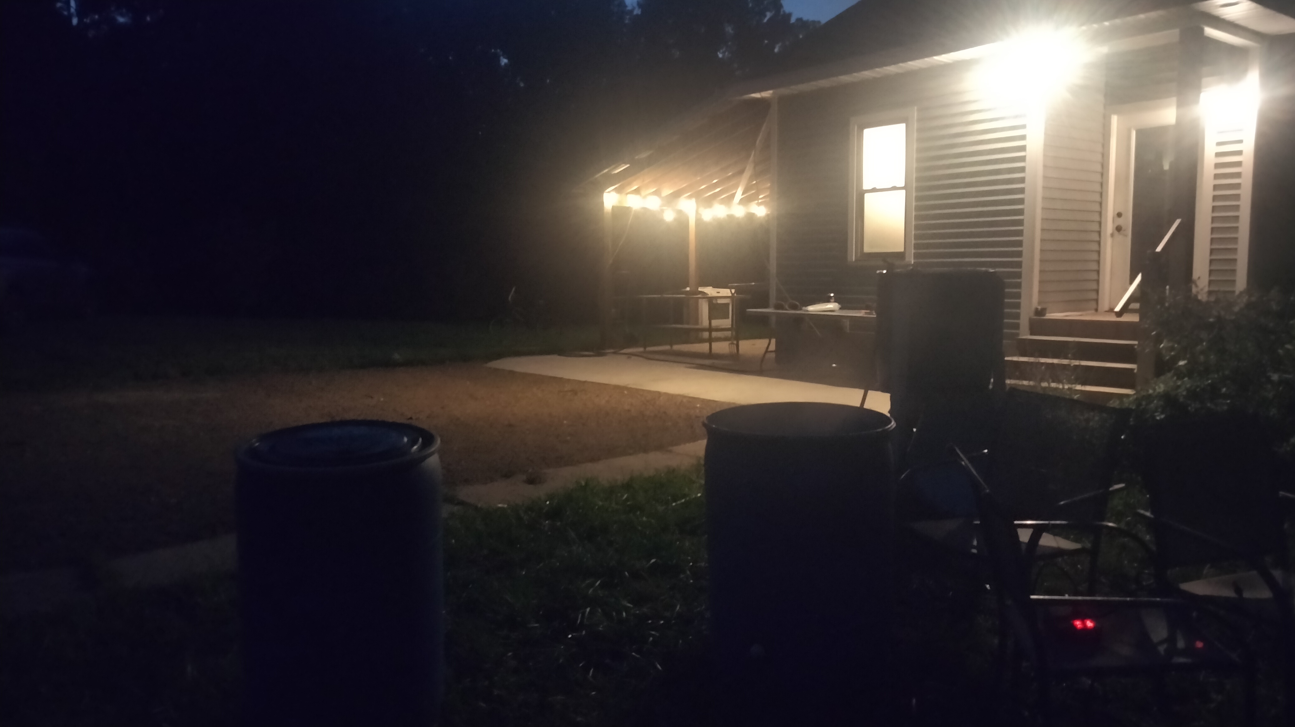 A dark house with porch lights on. There is some equipment visible in the foreground.
