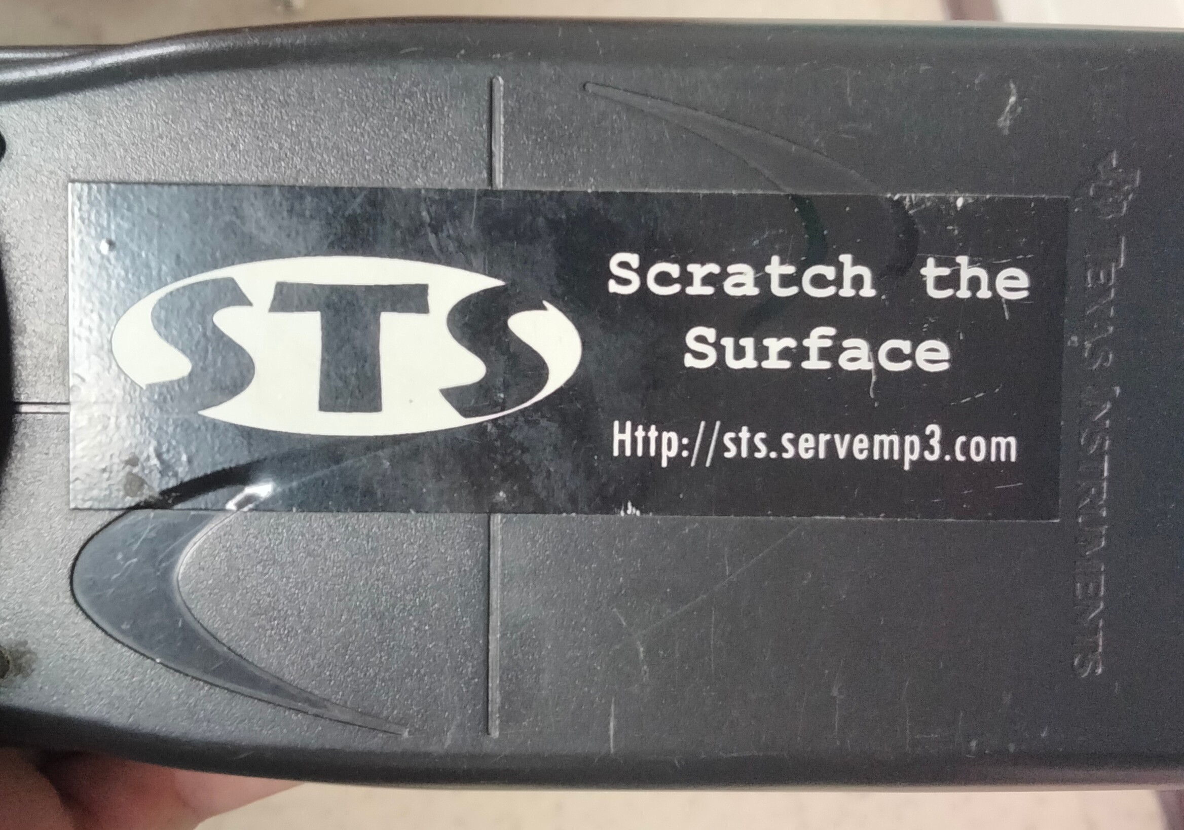 A vinyl sticker with Scratch the Surface and a website url on the back of a calculator 