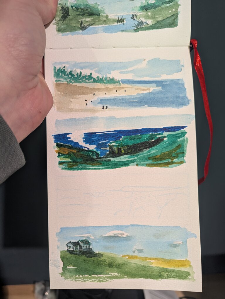 Three more painted bookmarks. The first is another beach scene. Water laps on shore with people near the shoreline. A seascape from the top of a cliff. The ocean lies below with the cliff edge visible in the middle distance. A white house on a green hill with a golden pasture in the background. There is a fourth, unfinished sketch on this page.
