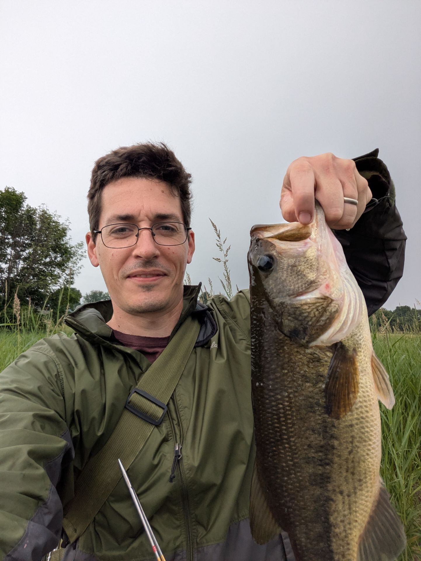 A selfie where I am holding a largemouth bass up to the camera.